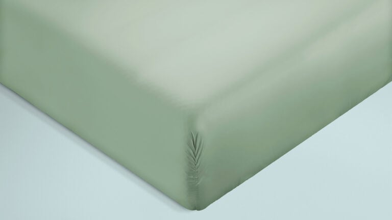 Zoom in op een hoek van een matras met een zacht lichtgroen hoeslaken