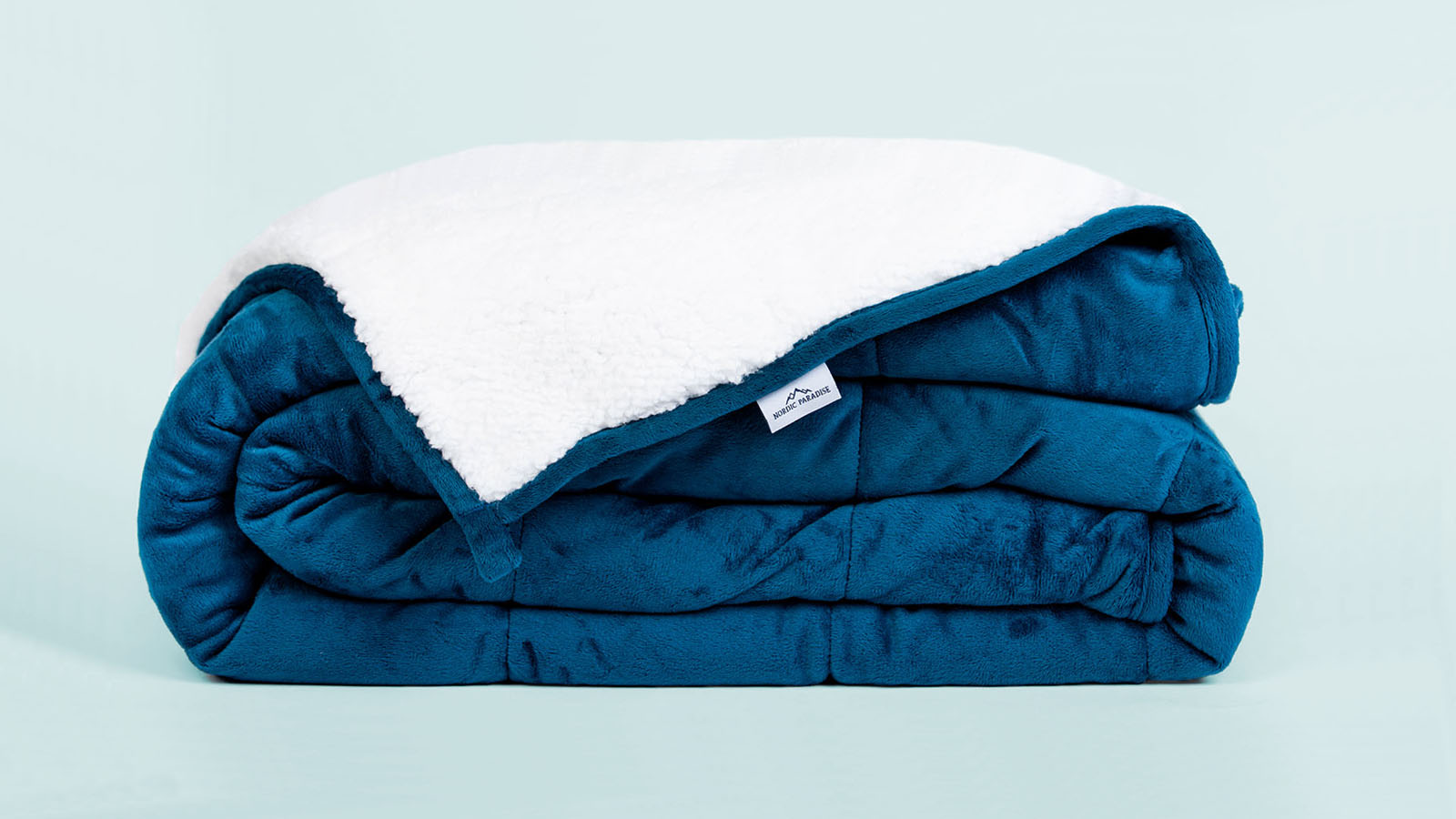 Folded blue weighted blanket with flipped corner on light blue background
