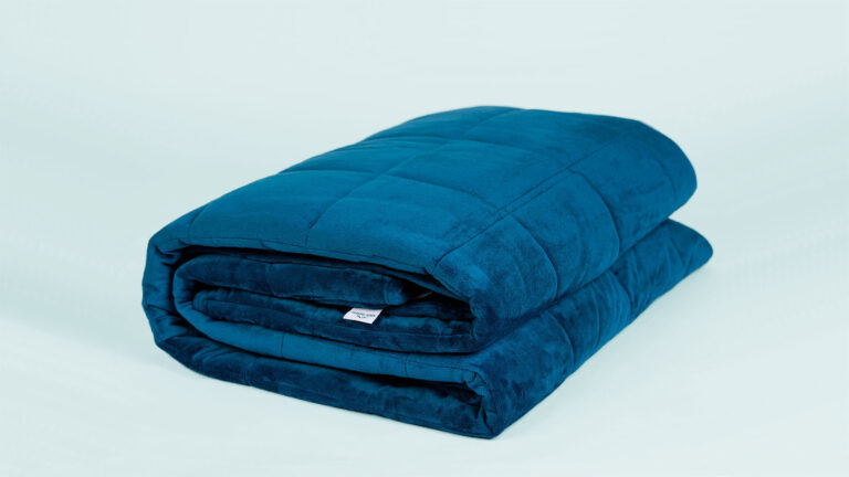 Folded blue weighted blanket on light blue background