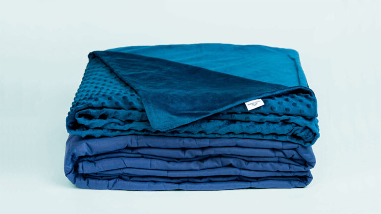 Folded blue weighted blanket with a minky dotted cover on blue background