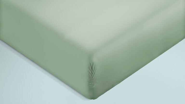Zoom in op een hoek van een matras met een zacht lichtgroen hoeslaken