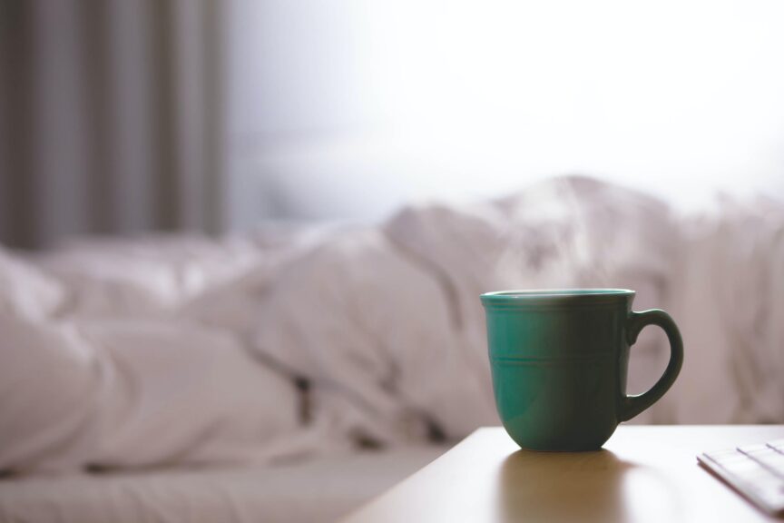 Bedroom with a white down duvet and a table with mug on it