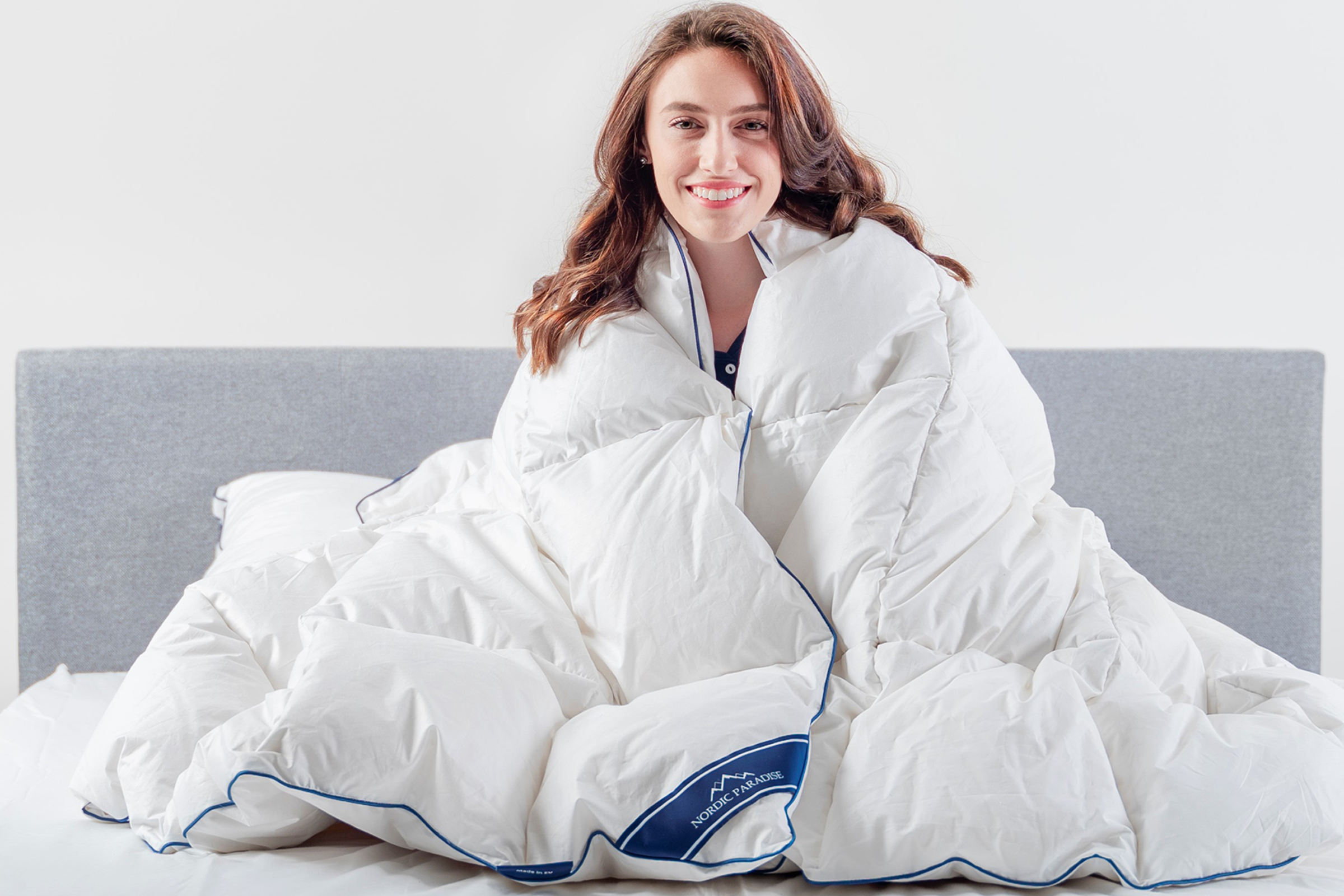 Girl tucked in a down duvet on a white bed
